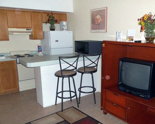 A well equipped kitchen with a breakfast bar alongside a television.