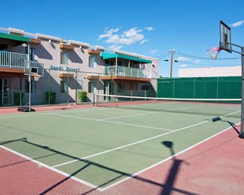 Outdoor recreation area with tennis court and basketball nets alongside multiple balconies.