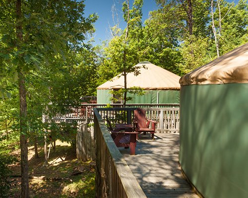 A view of multiple tree houses with private balconies and chaise lounge chairs surrounded by woods.