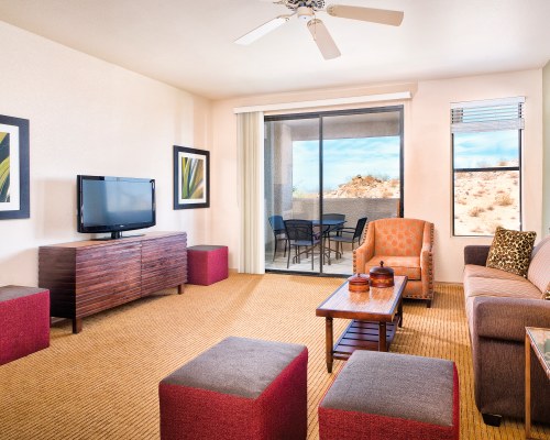 A WELL FURNISHED LIVING ROOM WITH A TELEVISION BALCONY AND PATIO FURNITURE.