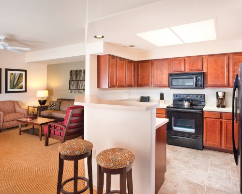 A WELL FURNISHED LIVING ROOM WITH AN OPEN PLAN KITCHEN AND A BREAKFAST BAR.