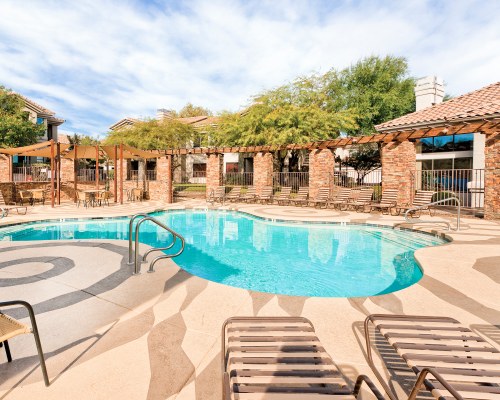 AN OUTDOOR SWIMMING POOL WITH CHAISE LOUNGE CHAIRS.