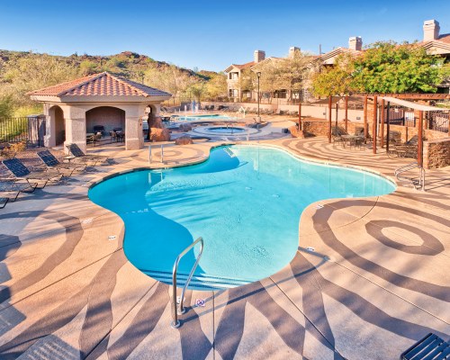 AN OUTDOOR SWIMMING POOL WITH CHAISE LOUNGE CHAIRS.