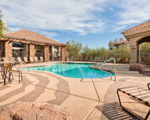 AN OUTDOOR SWIMMING POOL WITH CHAISE LOUNGE CHAIRS ALONGSIDE THE RESORT UNIT.