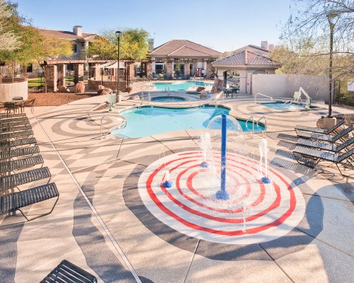 AN OUTDOOR SWIMMING POOL WITH A HOT TUB FOUNTAIN AND CHAISE LOUNGE CHAIRS.