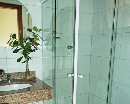 A bathroom with shower and single sink vanity.