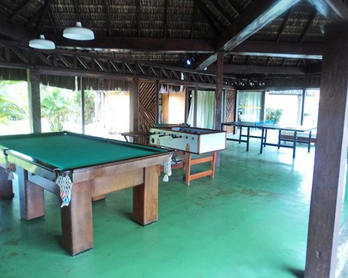 Thatched covered recreation area with pool table foosball and ping pong.