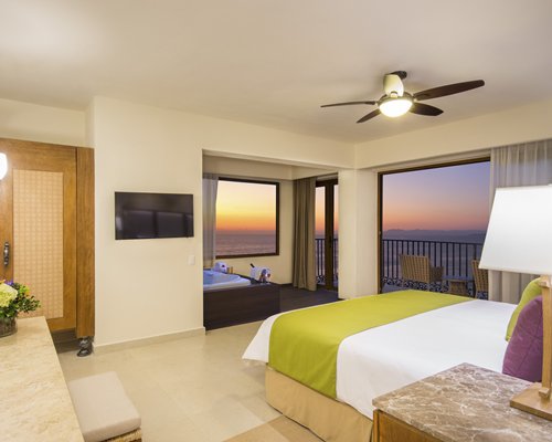 A well furnished large bedroom with a bathtub and balcony with patio furniture.