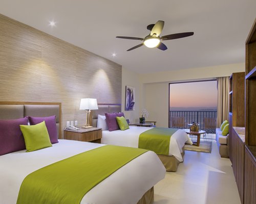 A well furnished bedroom with two beds and a balcony.