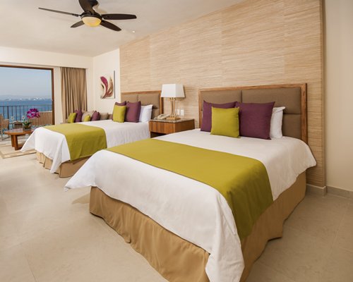 A well furnished bedroom with two twin beds balcony and ocean view.