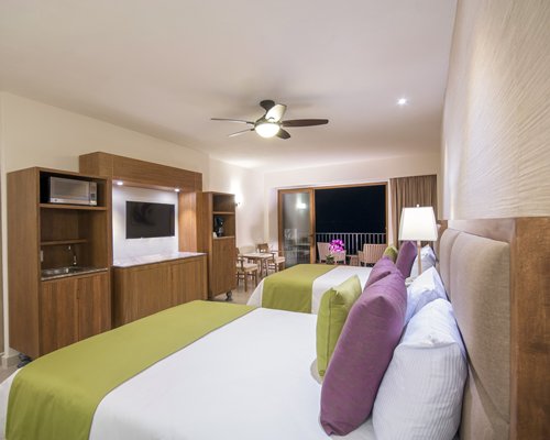 A well furnished bedroom with two beds television and balcony.
