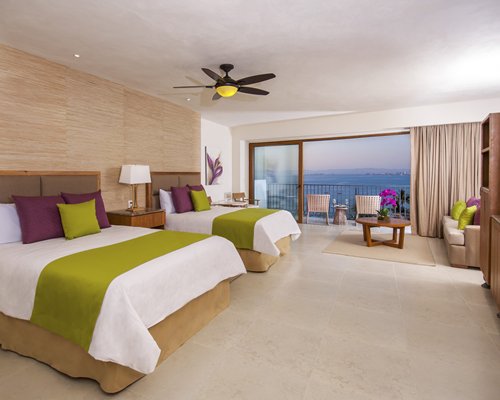 A well furnished bedroom with two beds and a balcony.
