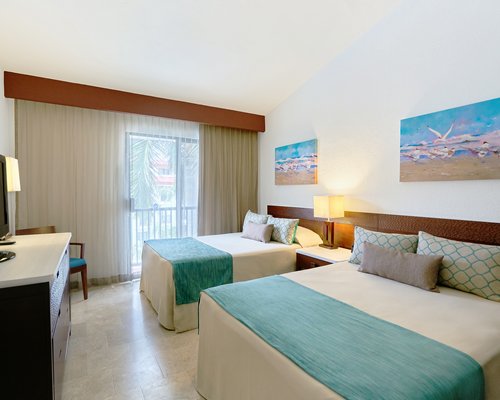A well furnished bedroom with two beds television and a balcony.