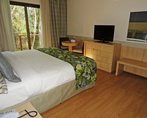 A well furnished bedroom with a television and a balcony.