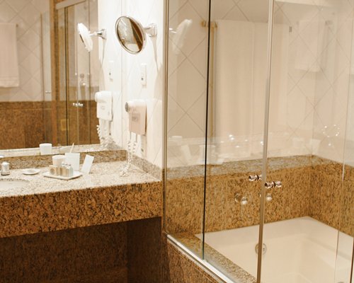 A bathroom with bathtub shower and single sink vanity.