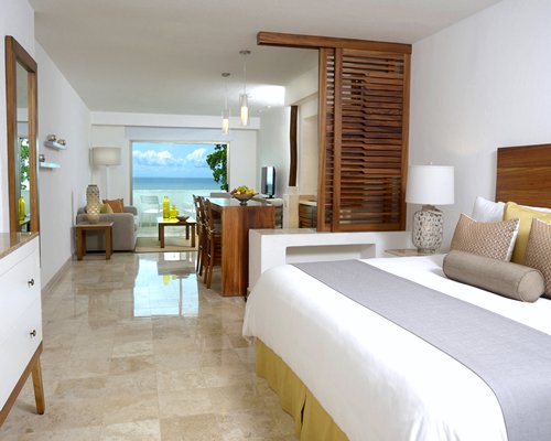 A well furnished bedroom alongside living room with a television.