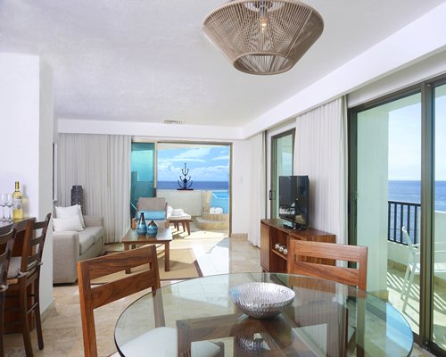 A well furnished living room with a glass top dining area and balcony.