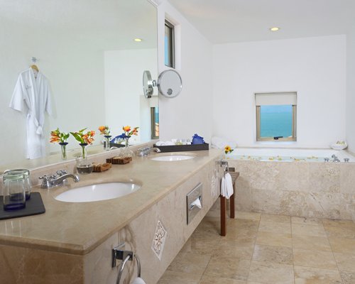 A bathroom with double sink vanity and a bathtub.