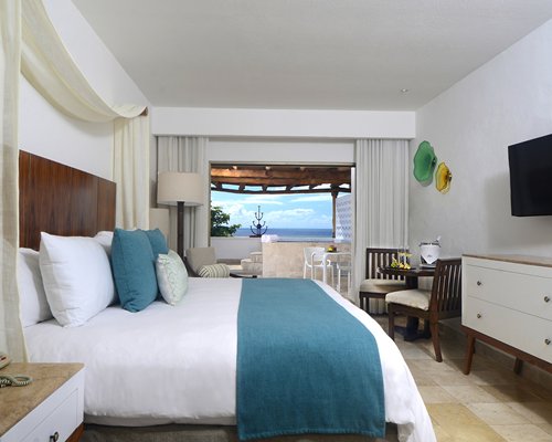 A well furnished bedroom with a television and a balcony.