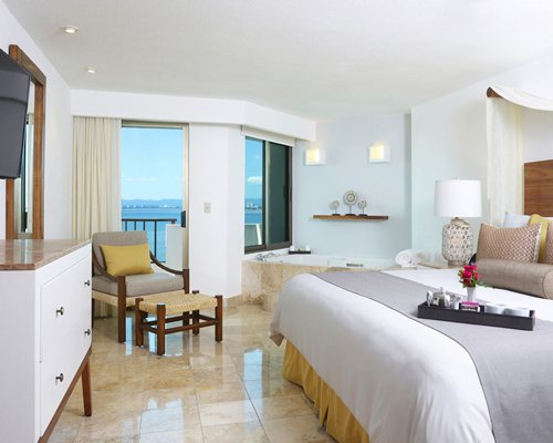 A well furnished bedroom with a television and bathtub.
