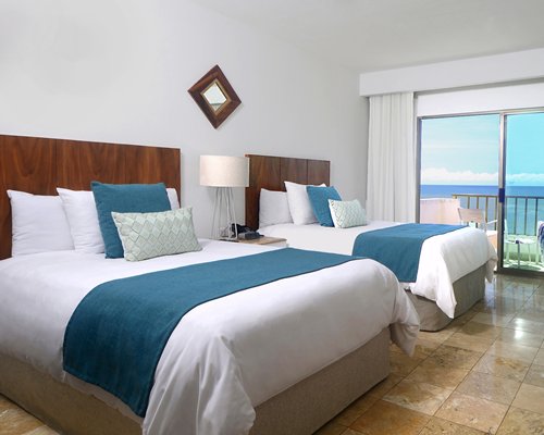 A well furnished bedroom with two beds and a balcony.