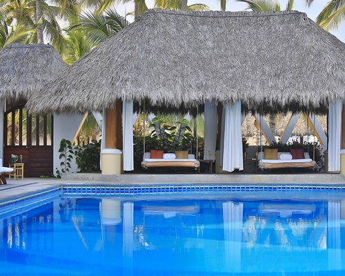 An outdoor swimming pool with thatched roof garden swing.