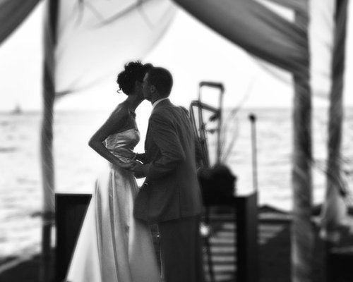 A couple kissing on a yacht at the ocean.
