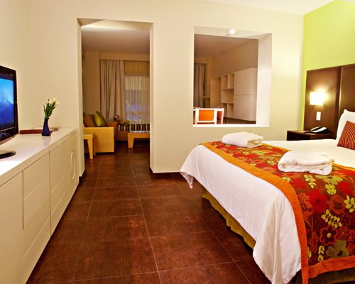 A well furnished bedroom with a king bed and television.