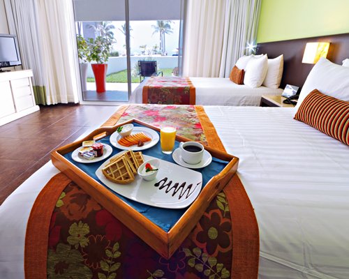 A well furnished bedroom with two double beds television and patio.