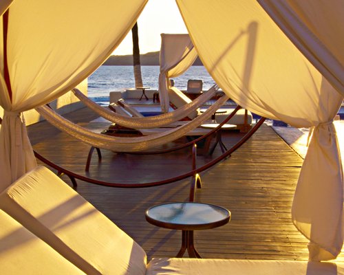 Lounge area with chaise lounge chairs and hammock alongside the ocean.