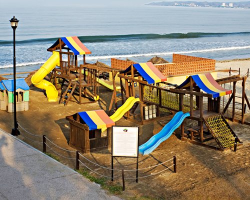 A view of an outdoor playscape alongside the ocean.