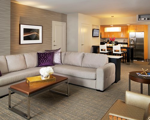 A well furnished living room with a television and an open plan kitchen.