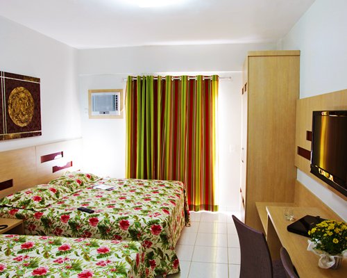 A well furnished bedroom with two twin beds television and outside view.
