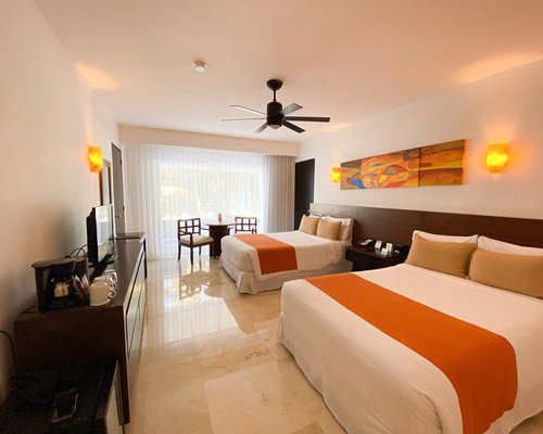 A well furnished bedroom with two twin beds television balcony and ocean view.