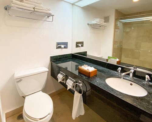 A well furnished bedroom with television and balcony view of the sea.