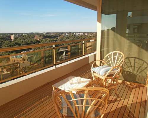 View of buildings and wooded area from the balcony with patio furniture.