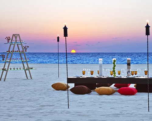 A beach side restaurant with beverages alongside the sea at dusk.