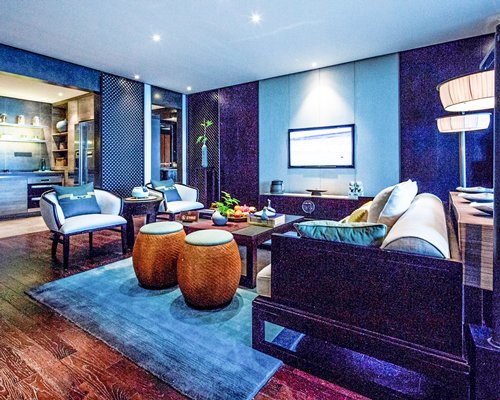 A well furnished bedroom with a television alongside kitchen.