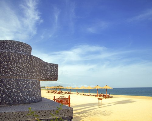 View of beach with chaise lounge chairs and sunshades alongside the sea.