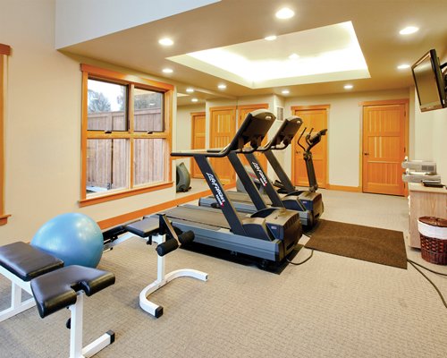 A well equipped indoor fitness center with a television.