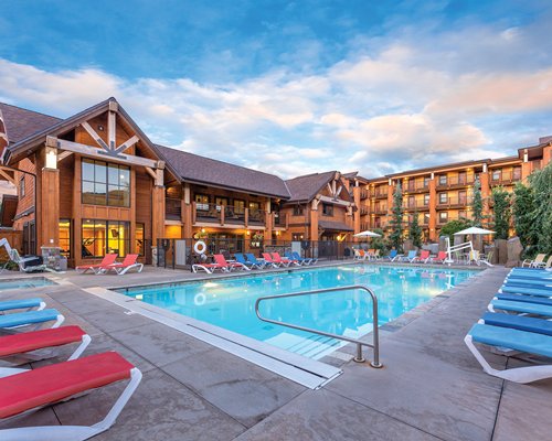 An outdoor swimming pool with chaise lounge chairs alongside multi story resort unit.