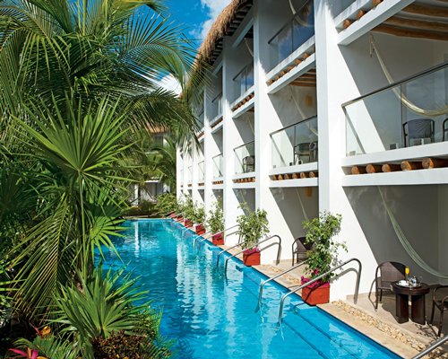 Outdoor swimming pool with patio chairs alongside multiple balconies.