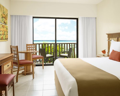A well furnished bedroom with a balcony view of the sea.