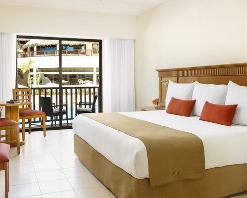 A well furnished bedroom with a king bed and balcony.