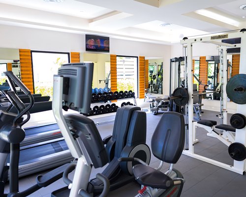 A well equipped indoor fitness center with television.