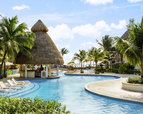 An outdoor swimming pool with chaise lounge chairs and poolside bar alongside resort units.