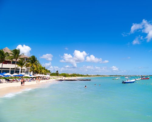 Beach view of the resort property with chaise lounge chairs and sunshades facing the ocean.