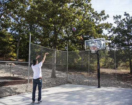 A man playing in an outdoor basketball court.