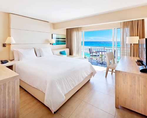 A well furnished bedroom with a television and balcony.