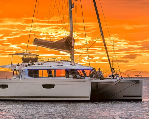 A view of a sailboat in the ocean at sunset